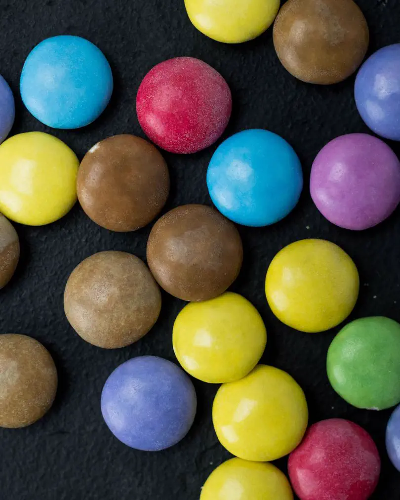 Coloured sugar-shelled sweets scattered on dark slate