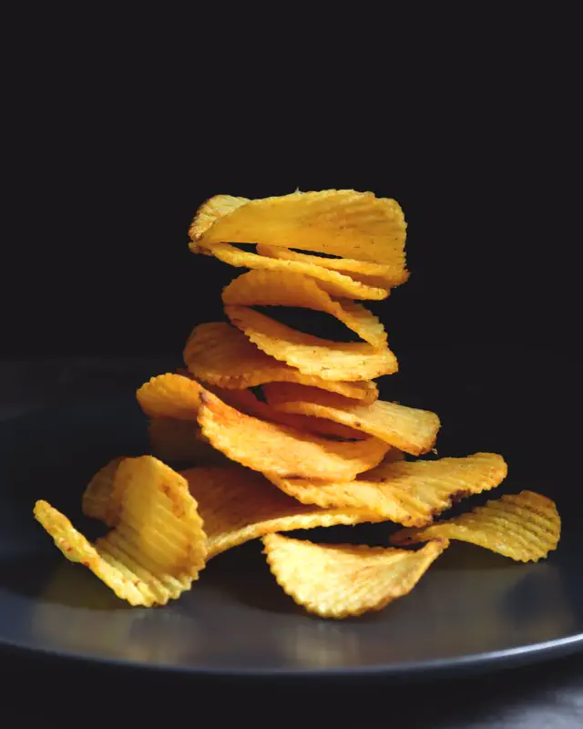 Ridged potato crisps on a black plate